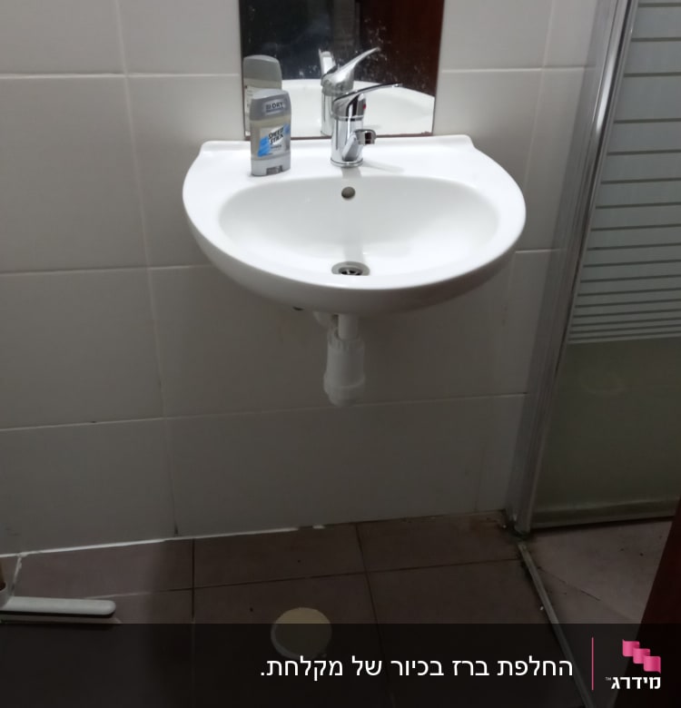 כיור עם ברז ומראה בחדר אמבטיה